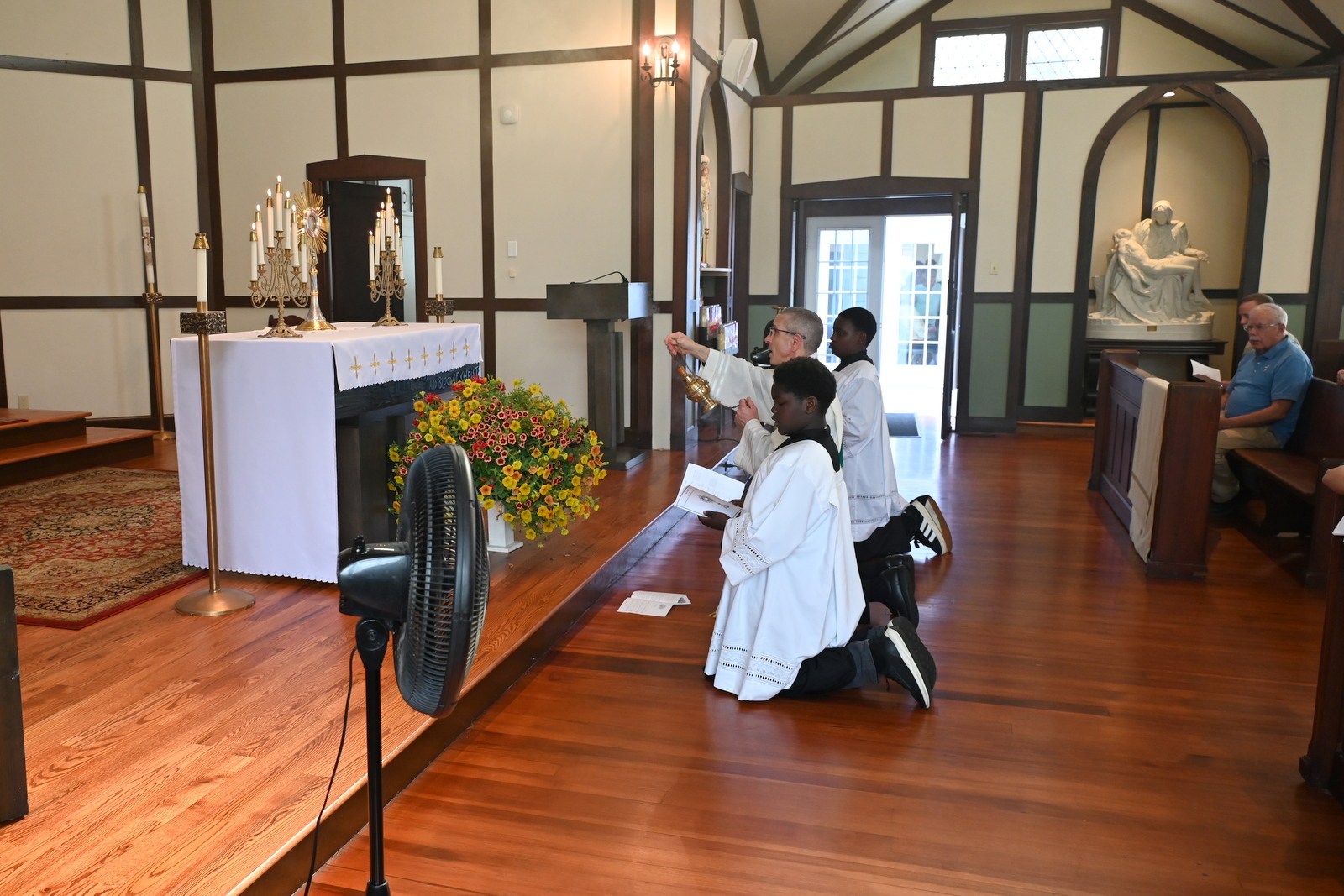 Bishop Deeley and altar servers kneel before the Blessed Sacrament for Benediction.