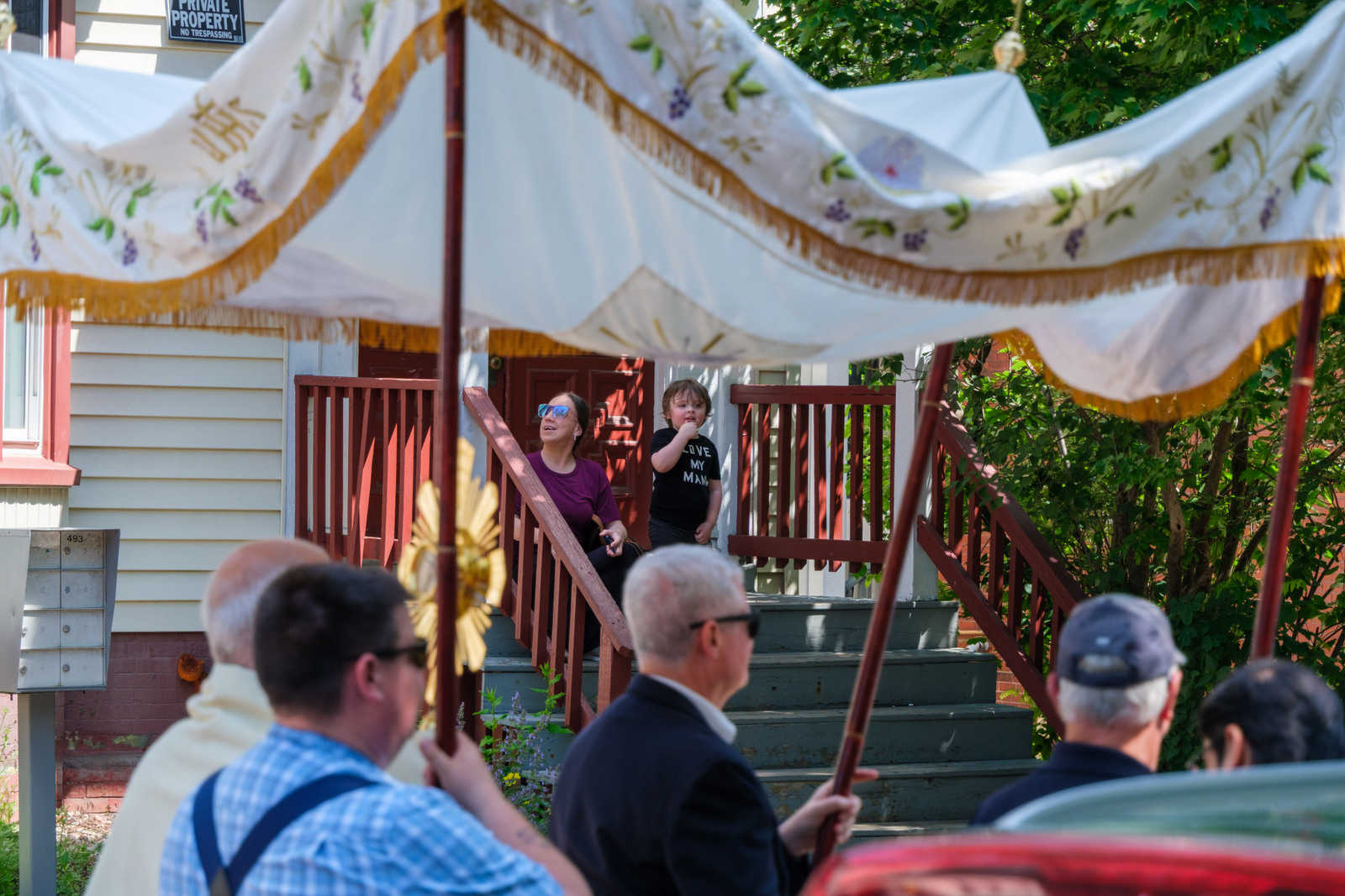 Mother and child watch from stairs as procession heads towards the Cathedral of the Immaculate Conception in Portland.