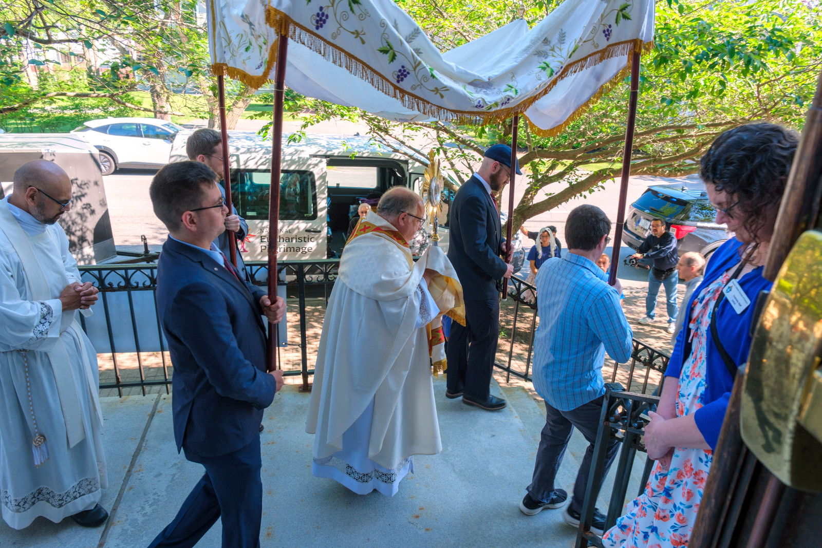 Father Phil Tracy carries the monstrance holding the Blessed Sacrament down the stairs of St. John the Baptist Church