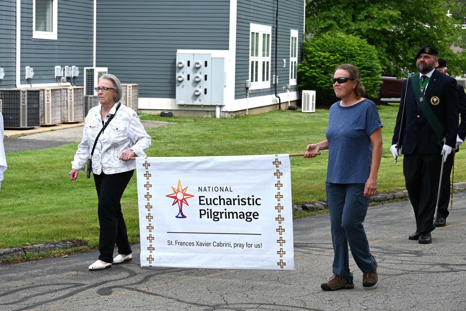 Paula Moses and another woman walk with the National Eucharistic Pilgrimage sign.