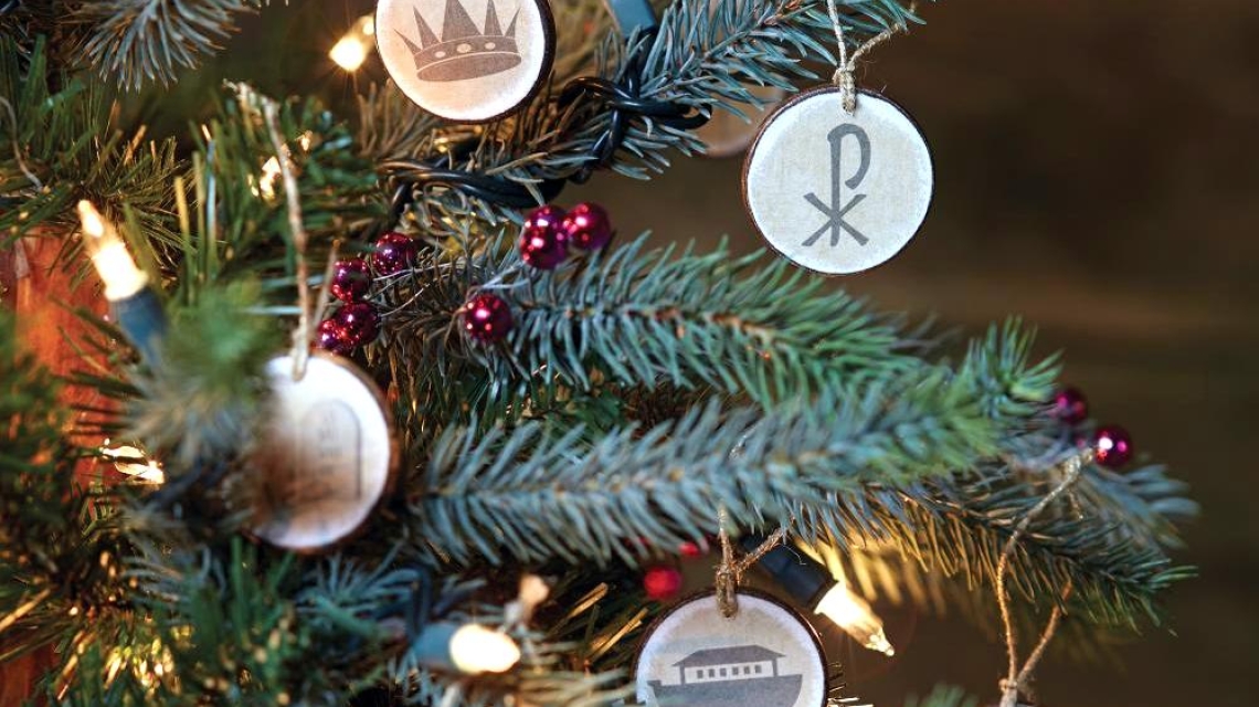 An evergreen tree branch with paper ornaments hung on it.