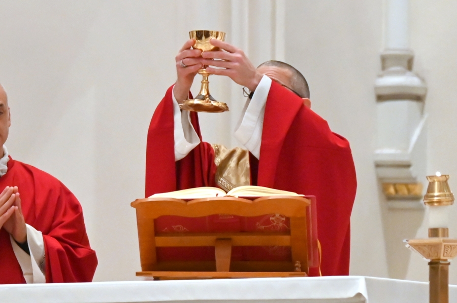Bishop James Ruggieri holds up the chalice with the blood of Christ.