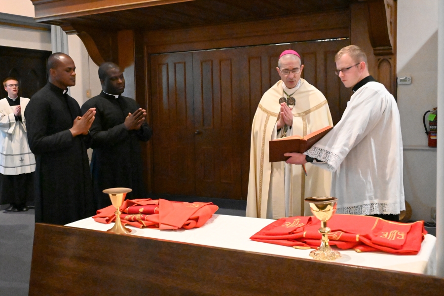 Bishop James Ruggieri blesses the vestments as the two deacons look on.