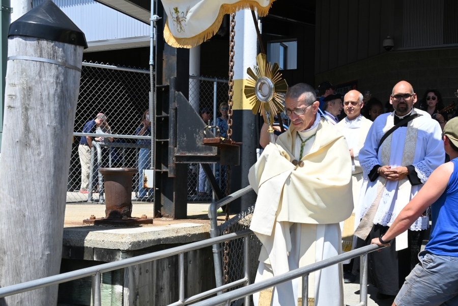Bishop Ruggieri, carrying the monstrance, boards the ferry.