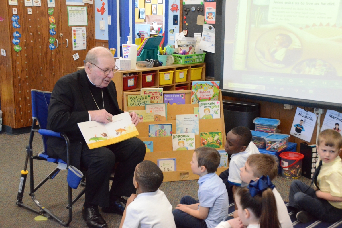 Bishop reading book to students