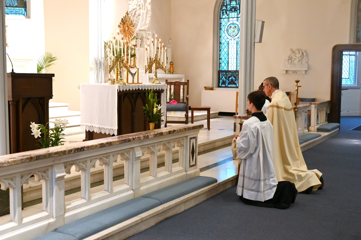 Bishop Ruggieri and altar servers kneel before the altar and the Blessed Sacrament.
