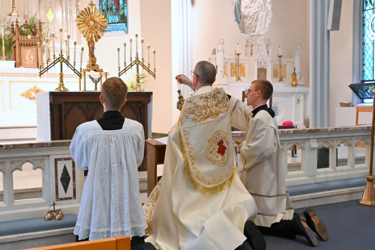 Bishop James Ruggieri incenses the altar and the monstrance. Seminarians Joseph Beale and Nicholas Hershbine are kneeling on either side of him.